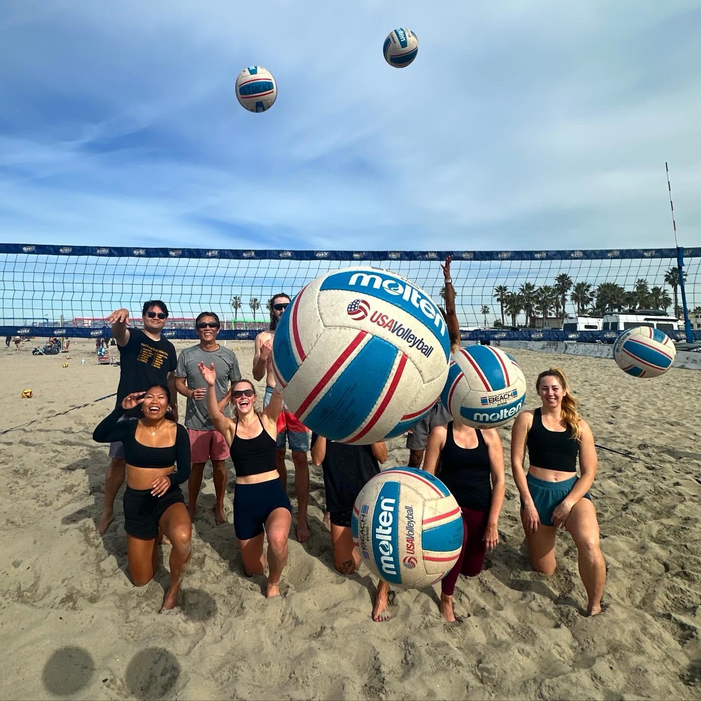 An OBVB community group laughing with volleyballs